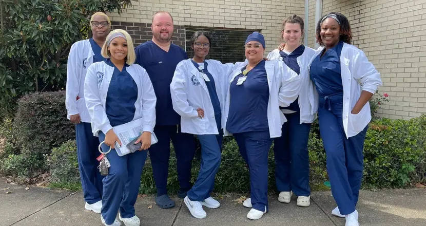 Group of Hering MSN students in white coats standing outdoors.